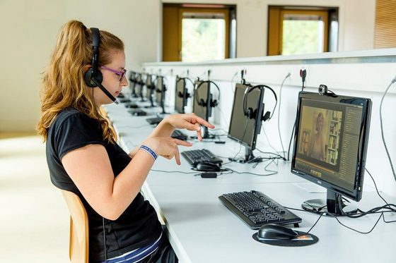 Eine junge Frau lernt Gebärdensprache in einem Computerraum.